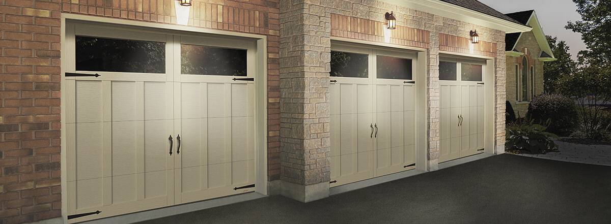 Traditional sang garage doors with overlay Eastman model with clear Panoramic windows on top of a red brick house