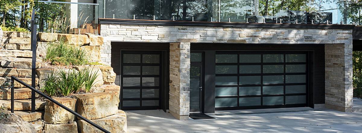 Porte de garage vitrée avec cadre noir modèle California sur une maison moderne avec fenêtre satiné 